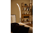 Lampada da terra LED curva illumina divano con cuscini e libreria in legno.