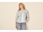 Donna con cardigan grigio, maglietta bianca e jeans blu.