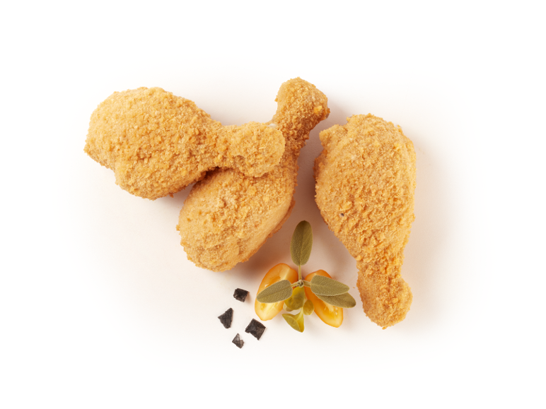 Cosce di pollo impanate con erbe aromatiche e pomodorini su sfondo scuro.