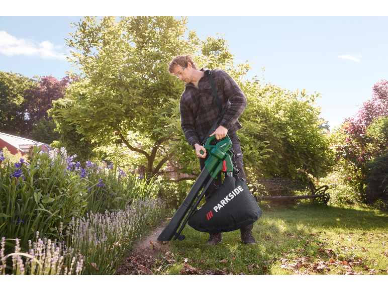 Uomo usa un aspirafoglie elettrico in un giardino.
