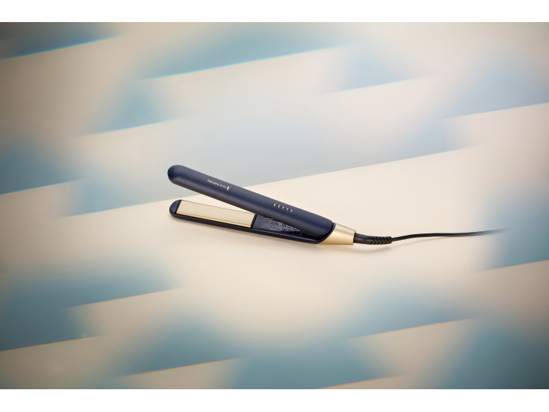 Piastra per capelli blu e oro con cavo.