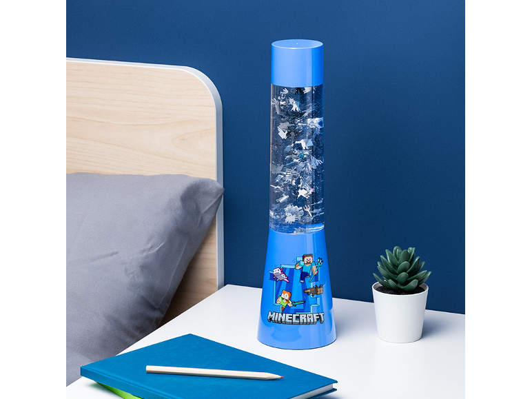 Lampada decorativa blu con disegni animati, accanto a un letto e una pianta.