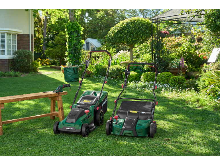 Due tosaerba e un tagliasiepi su una panca di legno in un giardino soleggiato.