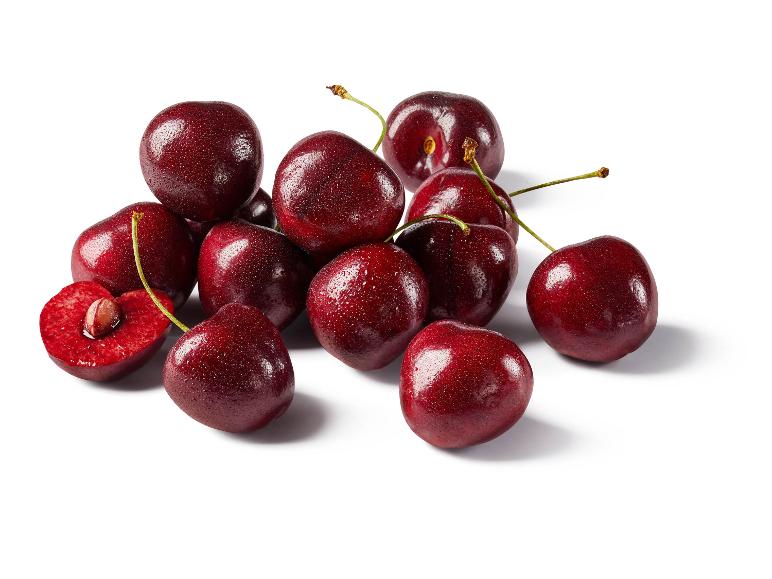 Pila di ciliegie fresche, rosso scuro con goccioline d'acqua, una tagliata a metà che rivela il nocciolo.