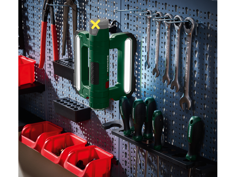 Utensile elettrico verde con luci LED, chiavi inglesi e cacciaviti su pannello forato.