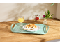 Vassoio con waffle, succo d'arancia, marmellata e fiori su un bancone di legno.