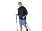 Uomo sorridente con felpa con cappuccio nera, pantaloncini blu e bastoncini da trekking.