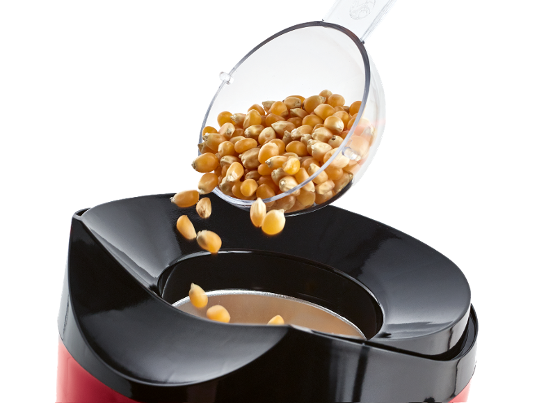 Chicchi di mais per popcorn versati da un misurino in una macchina per popcorn.