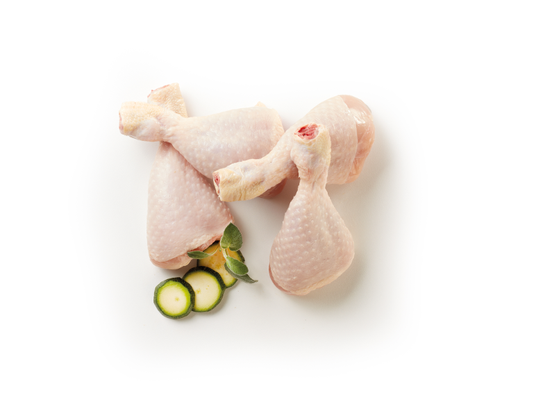 Fusi di pollo crudi con zucchine a fette e foglie di salvia su sfondo bianco.