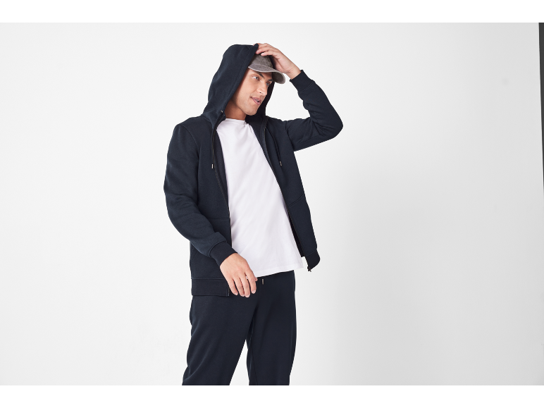 Uomo con felpa con cappuccio, maglietta bianca e pantaloni della tuta blu
