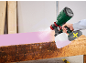 Pistola a spruzzo senza fili vernicia una panca di legno di rosa.