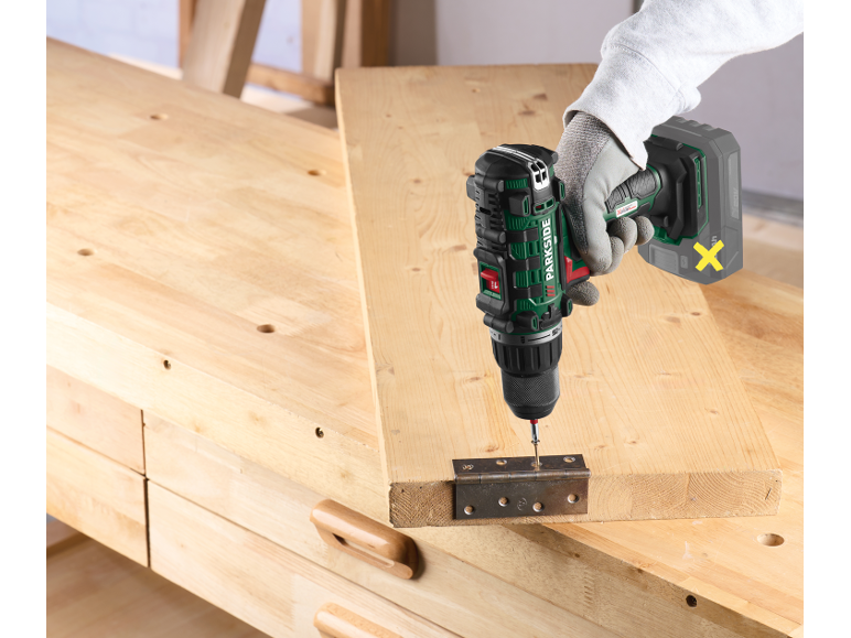 Trapano avvitatore a batteria che fissa una cerniera su una tavola di legno.