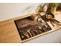 Tagliere in legno con spezie, pane e padella con verdure su un piano di lavoro.