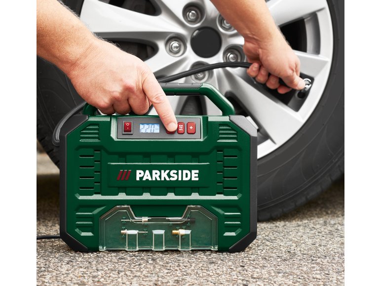 Uomo che gonfia un pneumatico d'auto con un compressore d'aria portatile verde.