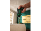 Mano che tiene un avvitatore a batteria verde con una punta, pronto per avvitare nel legno.