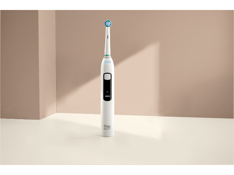 Spazzolino elettrico bianco con testina blu-verde su sfondo beige