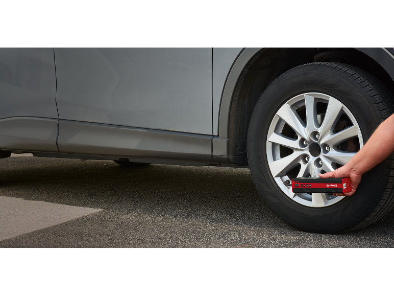 Uomo che gonfia un pneumatico dell'auto con un compressore portatile.