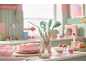 Utensili da cucina e torta rosa in una cucina dai toni pastello.