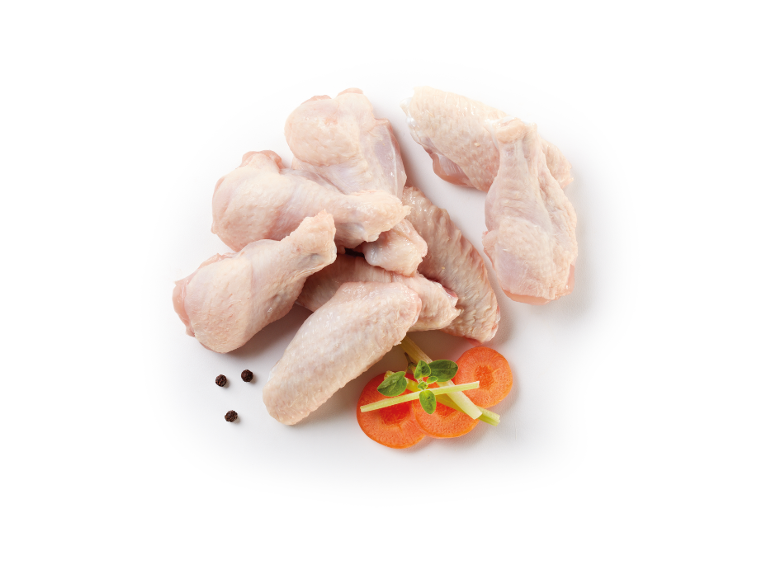 Ali di pollo crude con carote, sedano e grani di pepe nero su sfondo bianco.