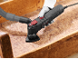 Utensile multifunzione con aspirapolvere che leviga una superficie di legno.