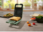 Tostapane verde con un toast in cucina, ingredienti intorno.