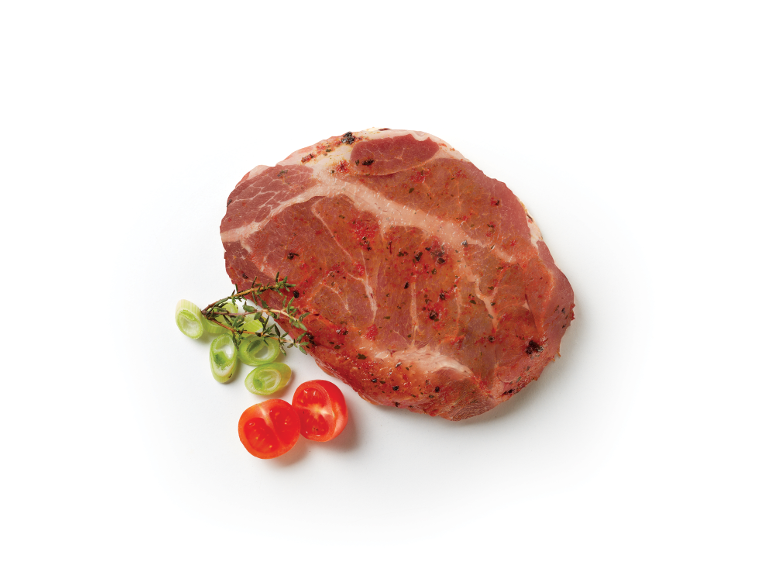 Bistecca di collo di maiale marinata con cipollotti e pomodorini su sfondo bianco.