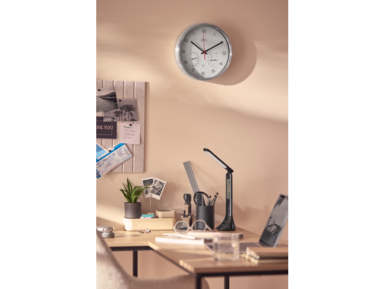 Scrivania da ufficio con orologio, lampada da tavolo, pianta e bacheca.