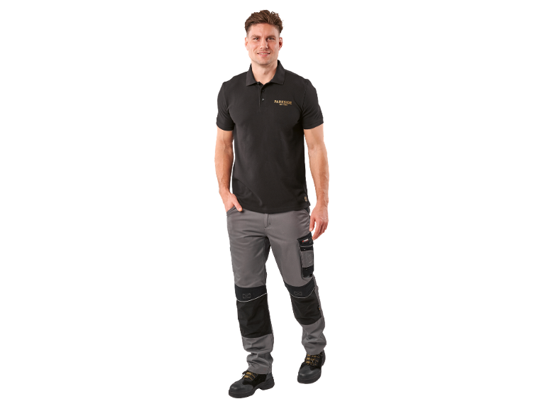 Uomo in polo nero con logo e pantaloni da lavoro grigi.
