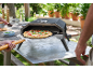 Forno per pizza da esterno con una pizza appena sfornata pronta per essere rimossa con una pala.