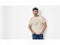 Uomo in t-shirt beige con stampa di tartaruga e testo 'Turtle Cove Island Resort'.