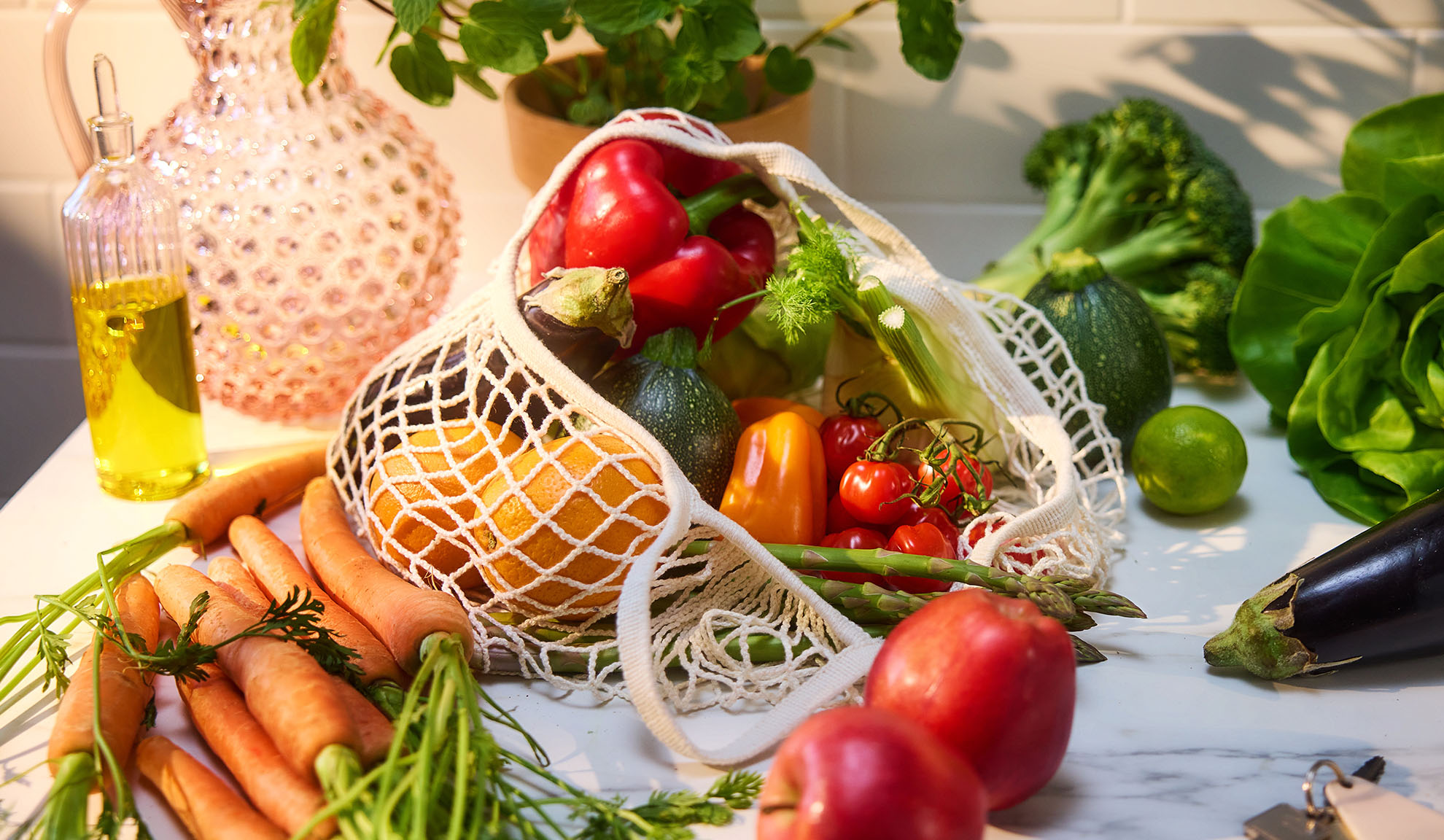 Verdure e frutta fresche, tra cui peperoni, arance e carote, in una borsa della spesa.