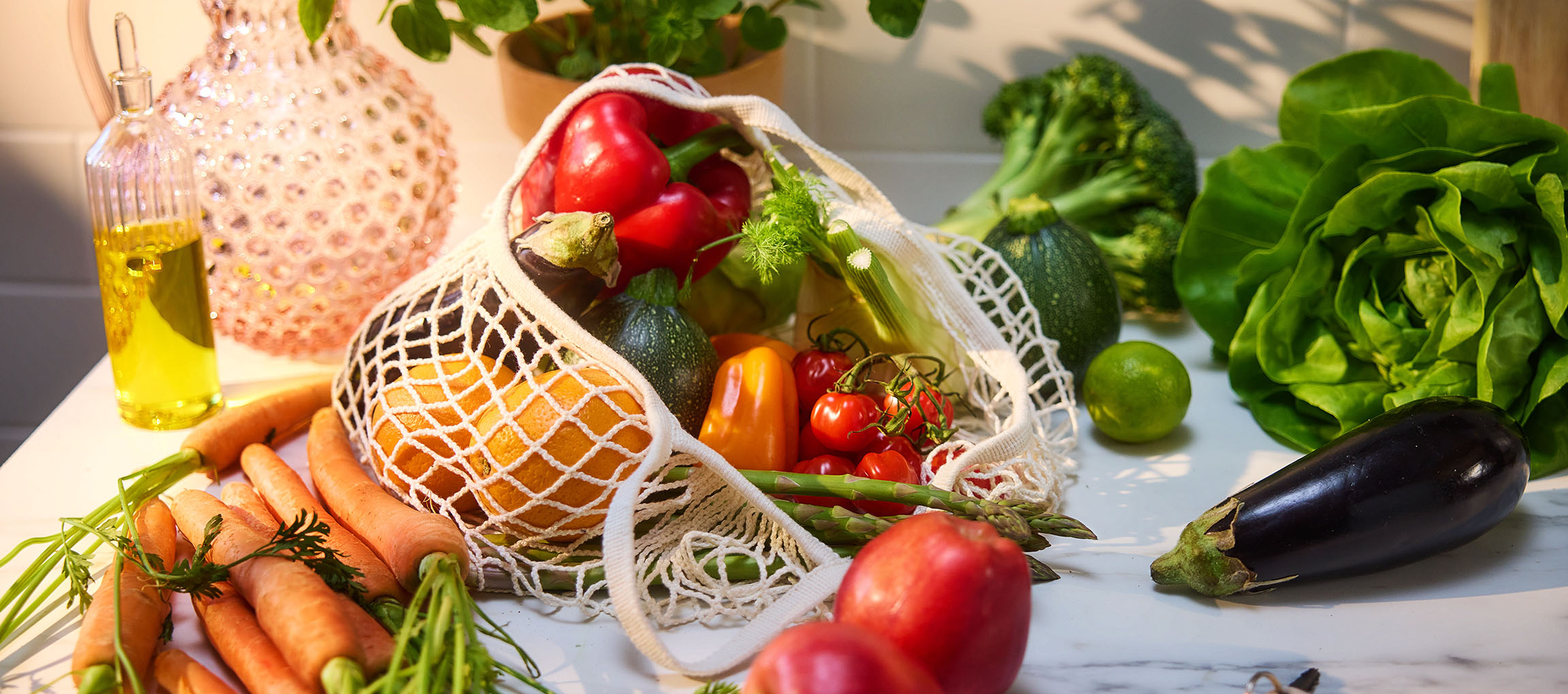 Verdure e frutta fresche, tra cui carote, peperoni, pomodori, lattuga e melanzane, su un tavolo.