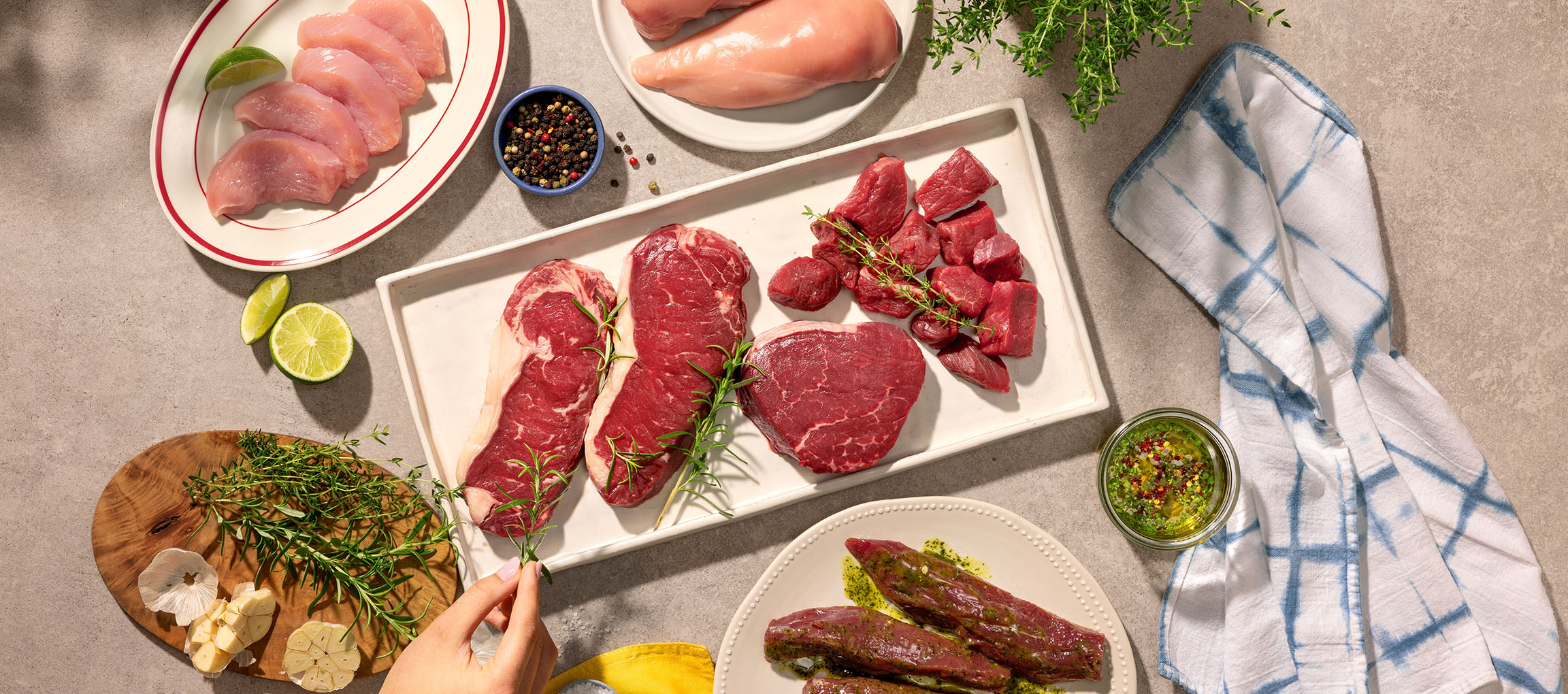 Vari tagli di carne cruda, inclusi pollo e manzo, con erbe aromatiche e spezie.