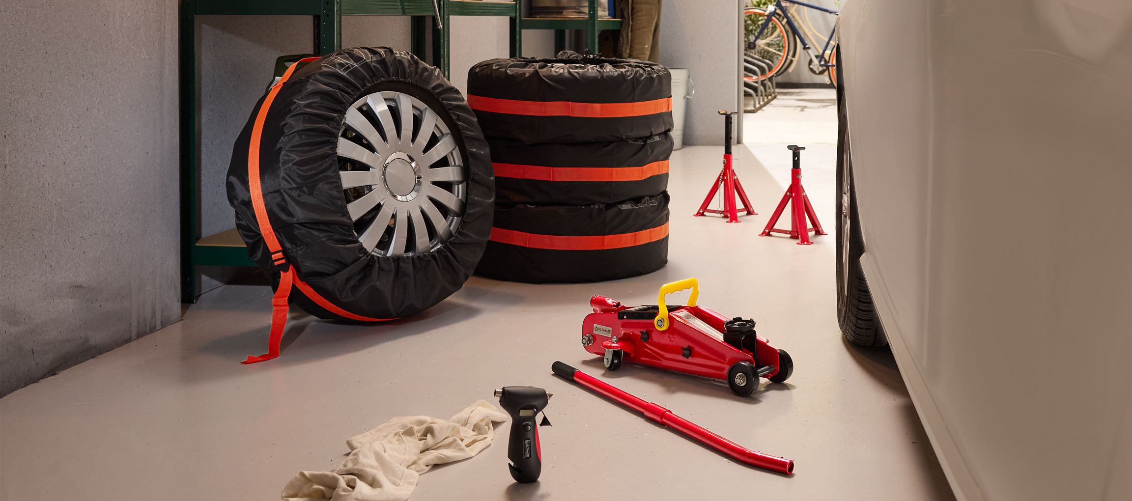 Pneumatici auto con coperture, cric e cavalletti in un garage.