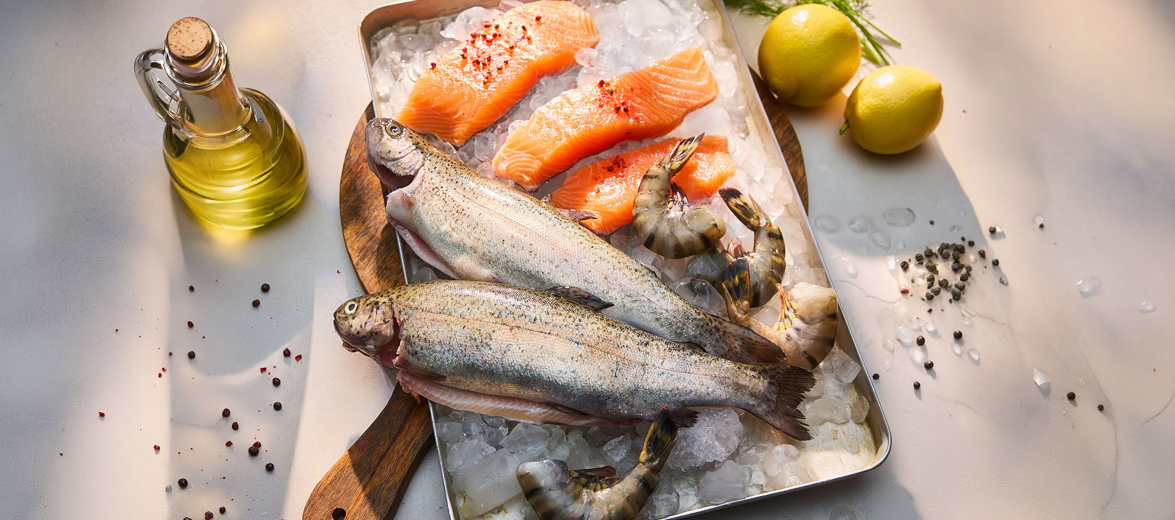 Pesce fresco e frutti di mare su ghiaccio, con limoni e olio.