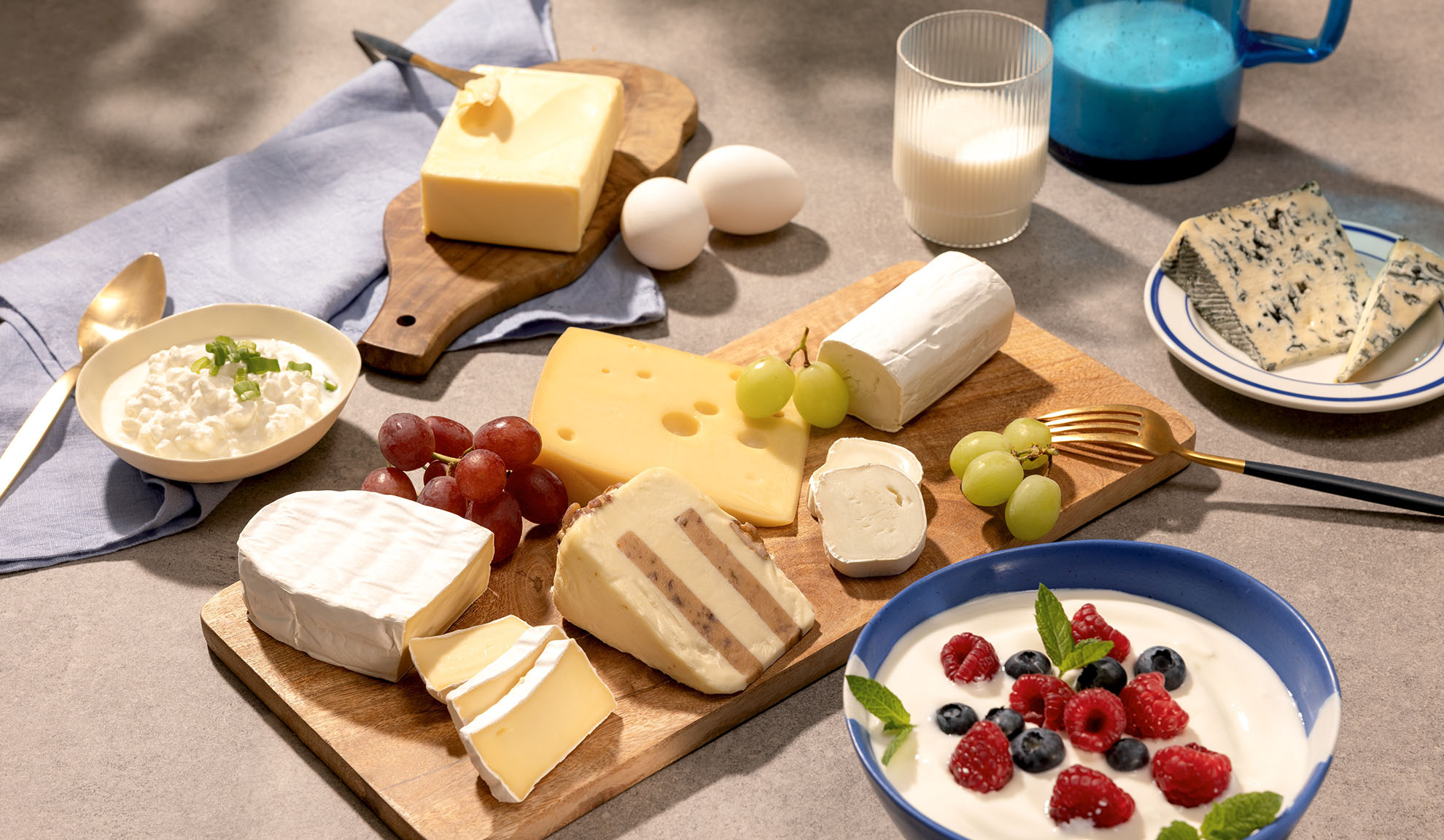 Una varietà di formaggi, uva e latticini come ricotta, latte e yogurt con frutti di bosco.