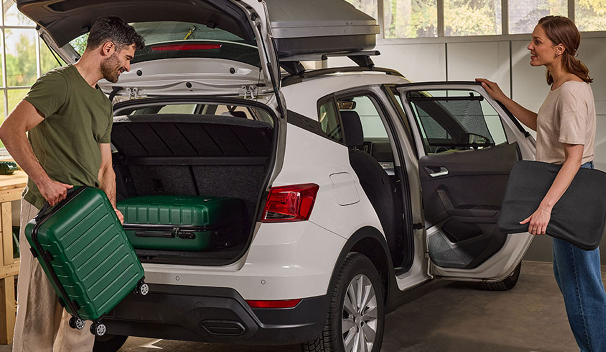 Coppia che prepara bagagli e accessori auto in un SUV bianco per un viaggio.