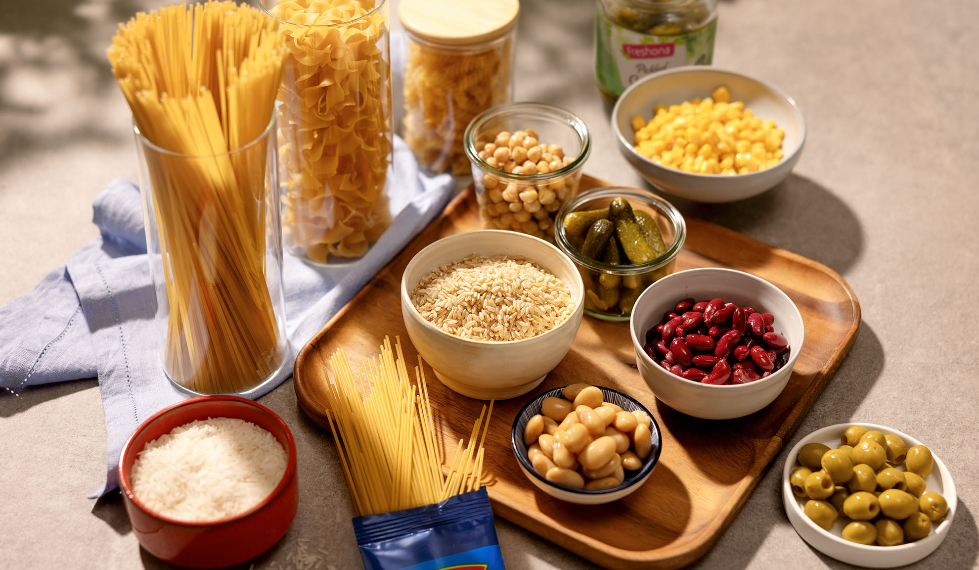 Assortimento di pasta secca, riso, ceci, fagioli, mais, cetriolini e olive.