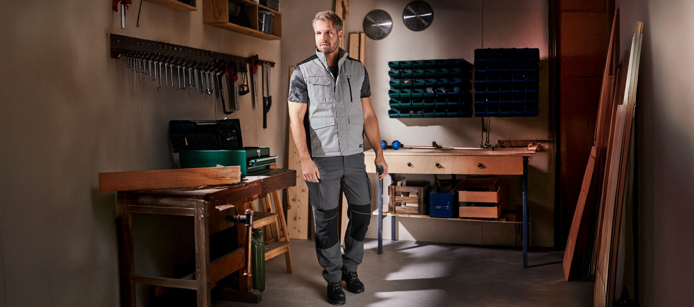 Un uomo in tuta da lavoro e gilet si trova in un laboratorio.