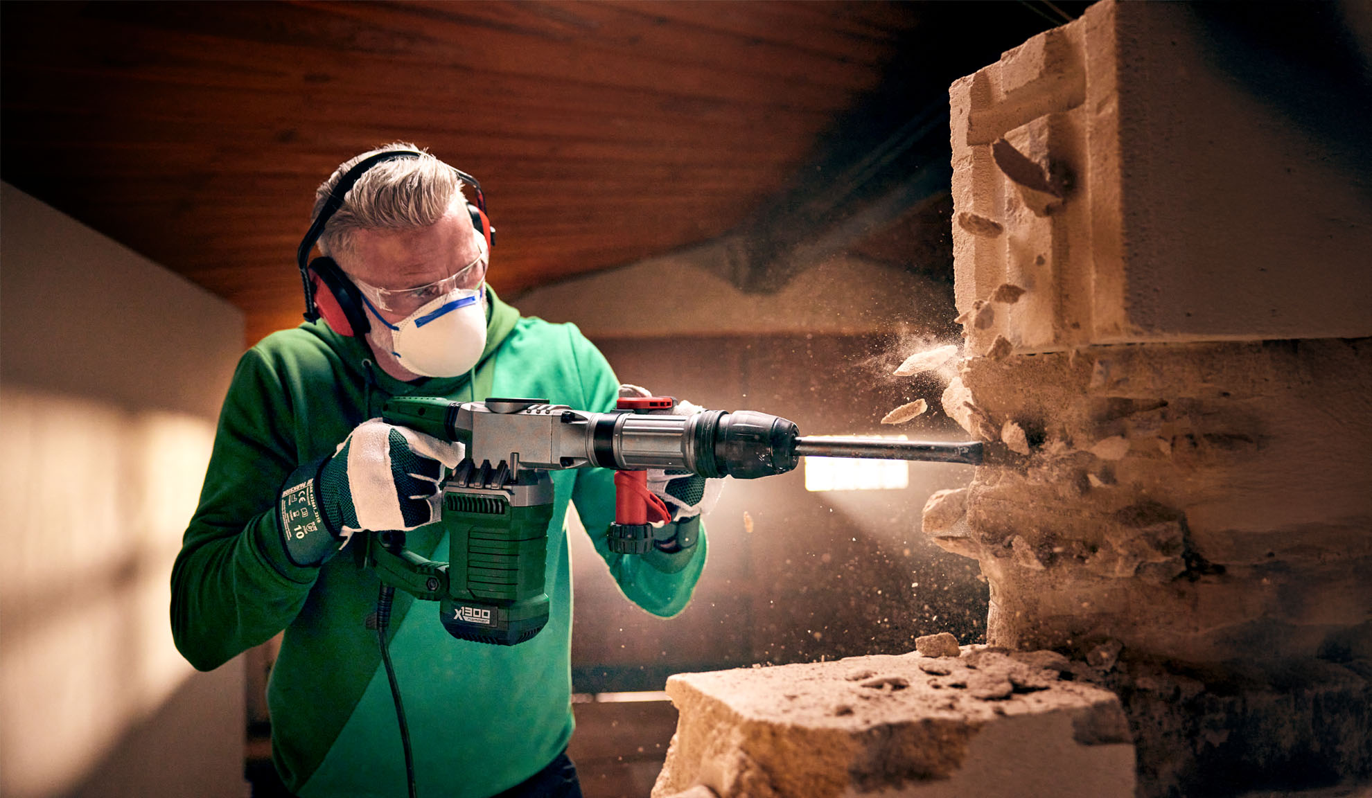 Un uomo usa un martello demolitore Worx X-BRUSHLESS per rompere un blocco di cemento.