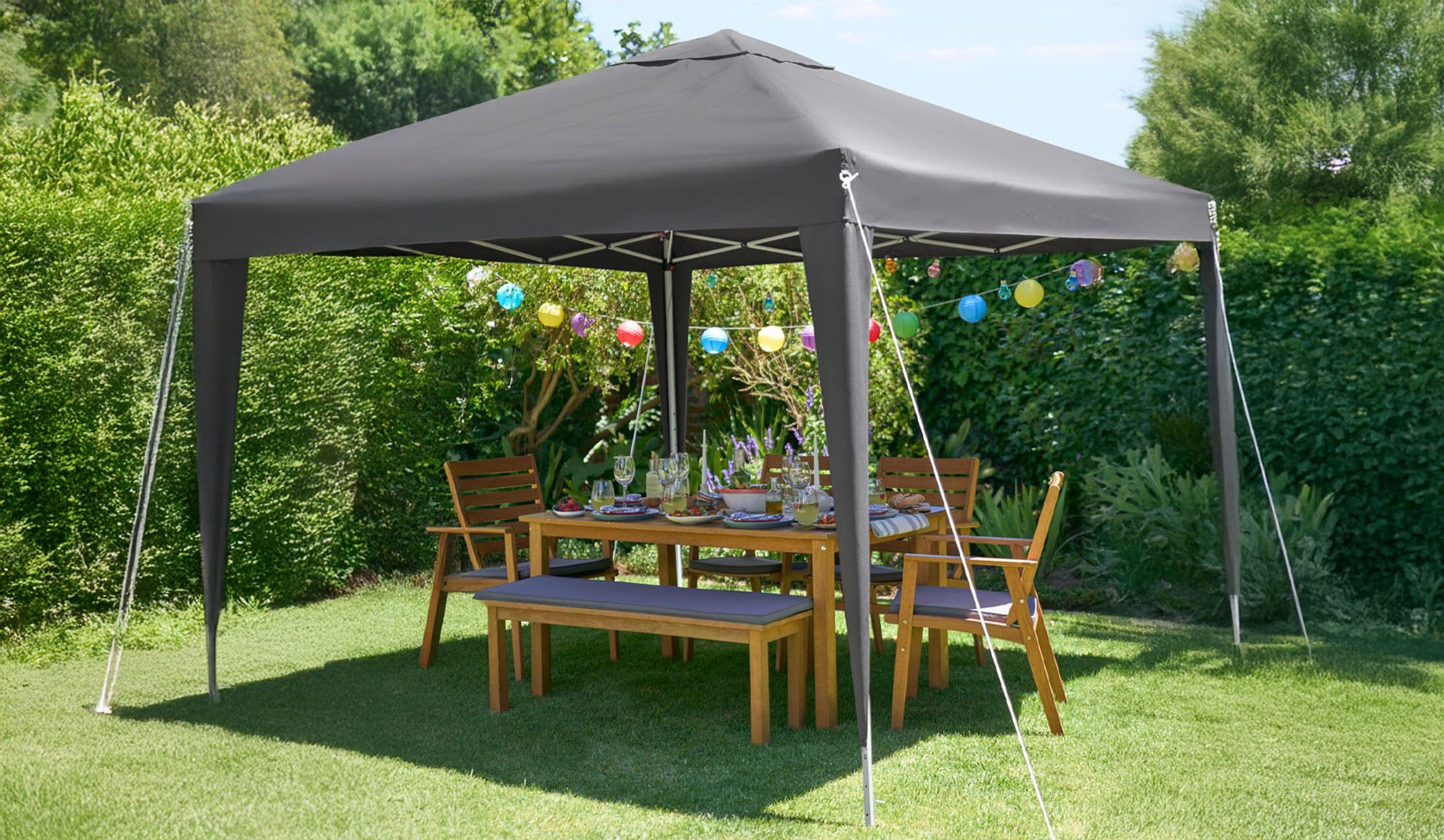 Gazebo da giardino grigio scuro con tavolo e sedie in legno.