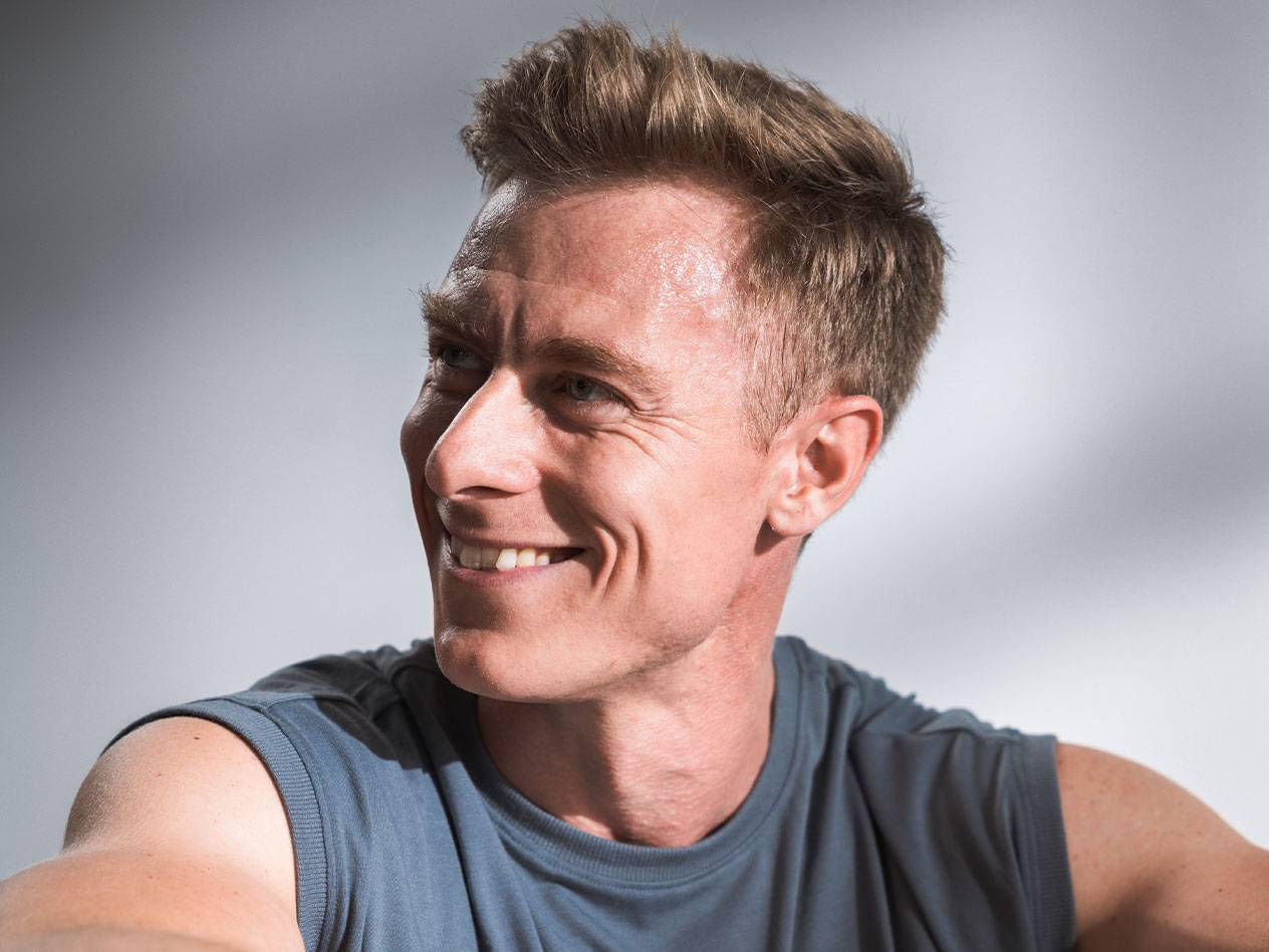 Un uomo sorridente con capelli corti e una canotta.