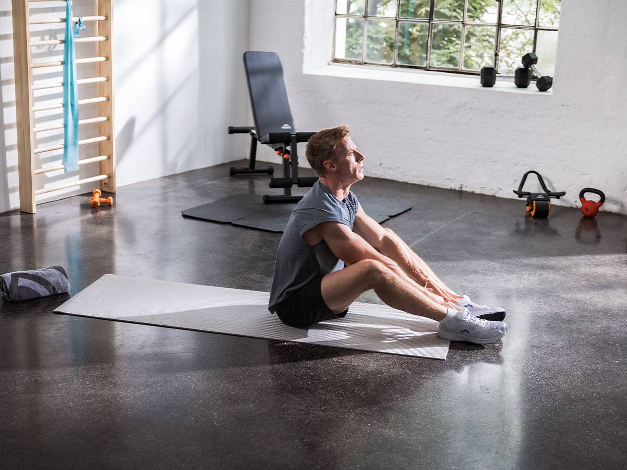 Un uomo si allunga su un tappetino da yoga in una palestra con attrezzature.