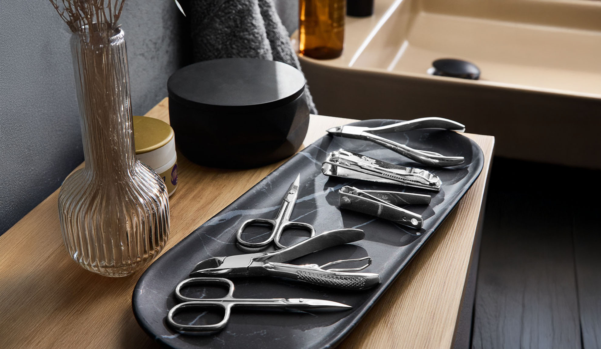Strumenti per manicure e pedicure su un vassoio vicino a un lavandino.