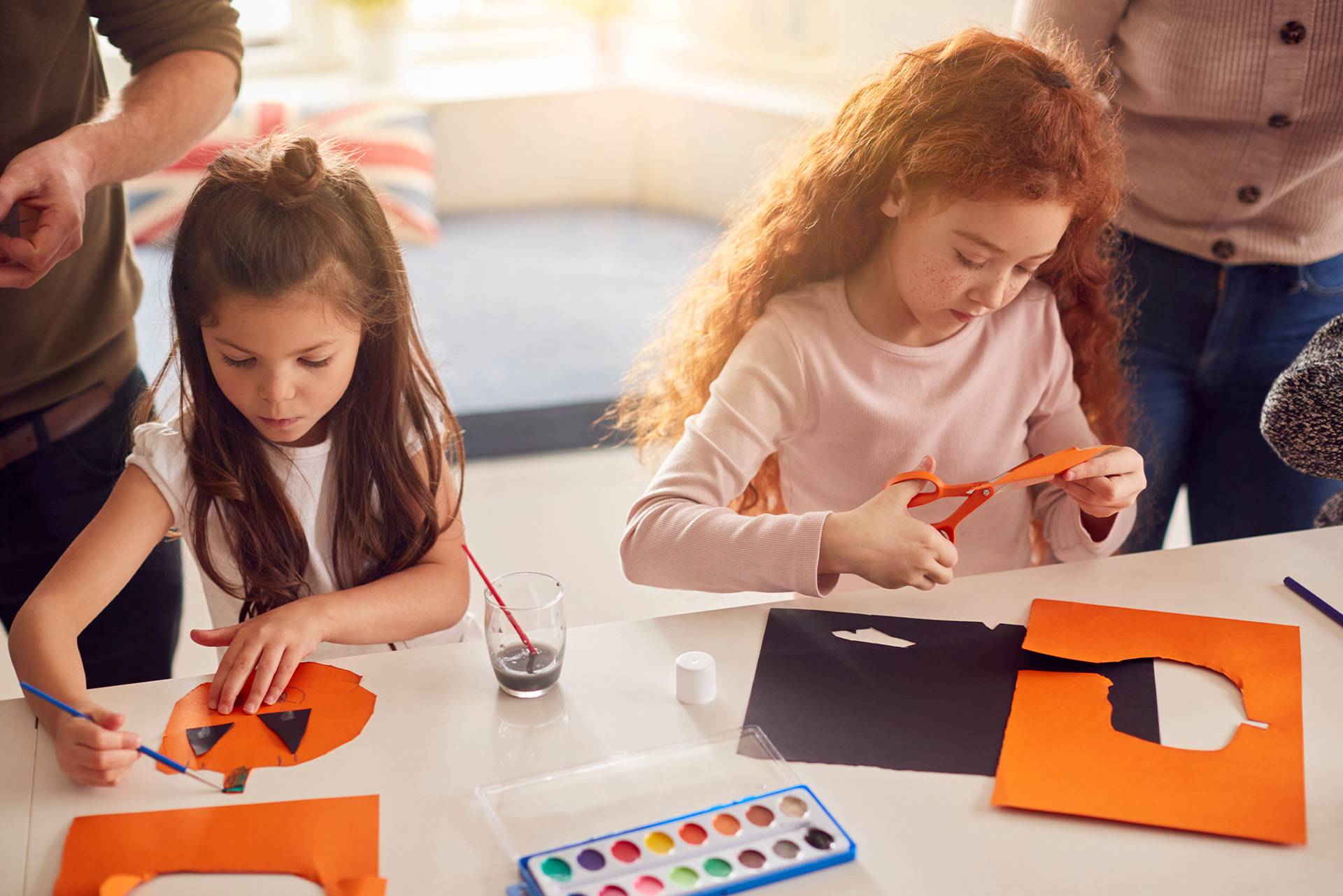 Due bambine creano decorazioni di Halloween con carta e colori.