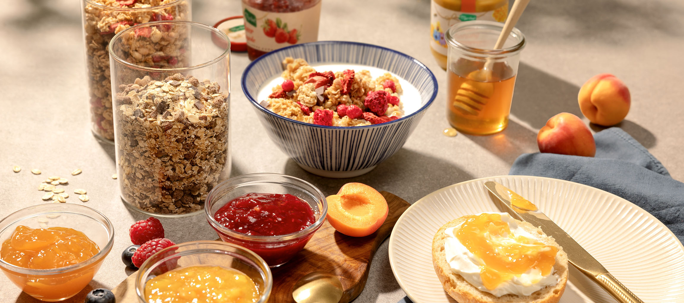 Colazione con muesli, latte, miele, marmellate e un panino con formaggio spalmabile.