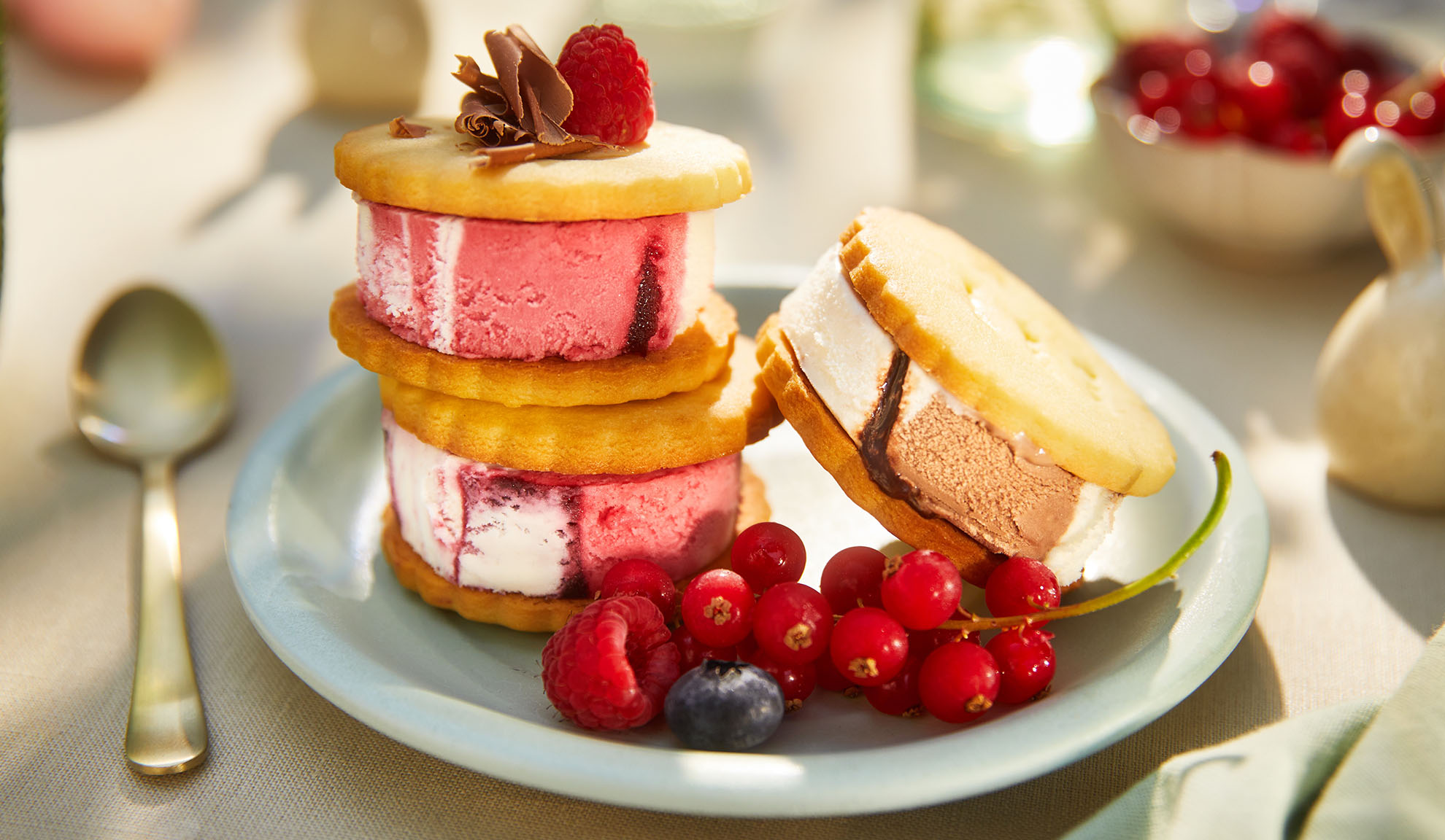 Sandwich di gelato con frutti di bosco su un piatto azzurro in un ambiente esterno soleggiato.