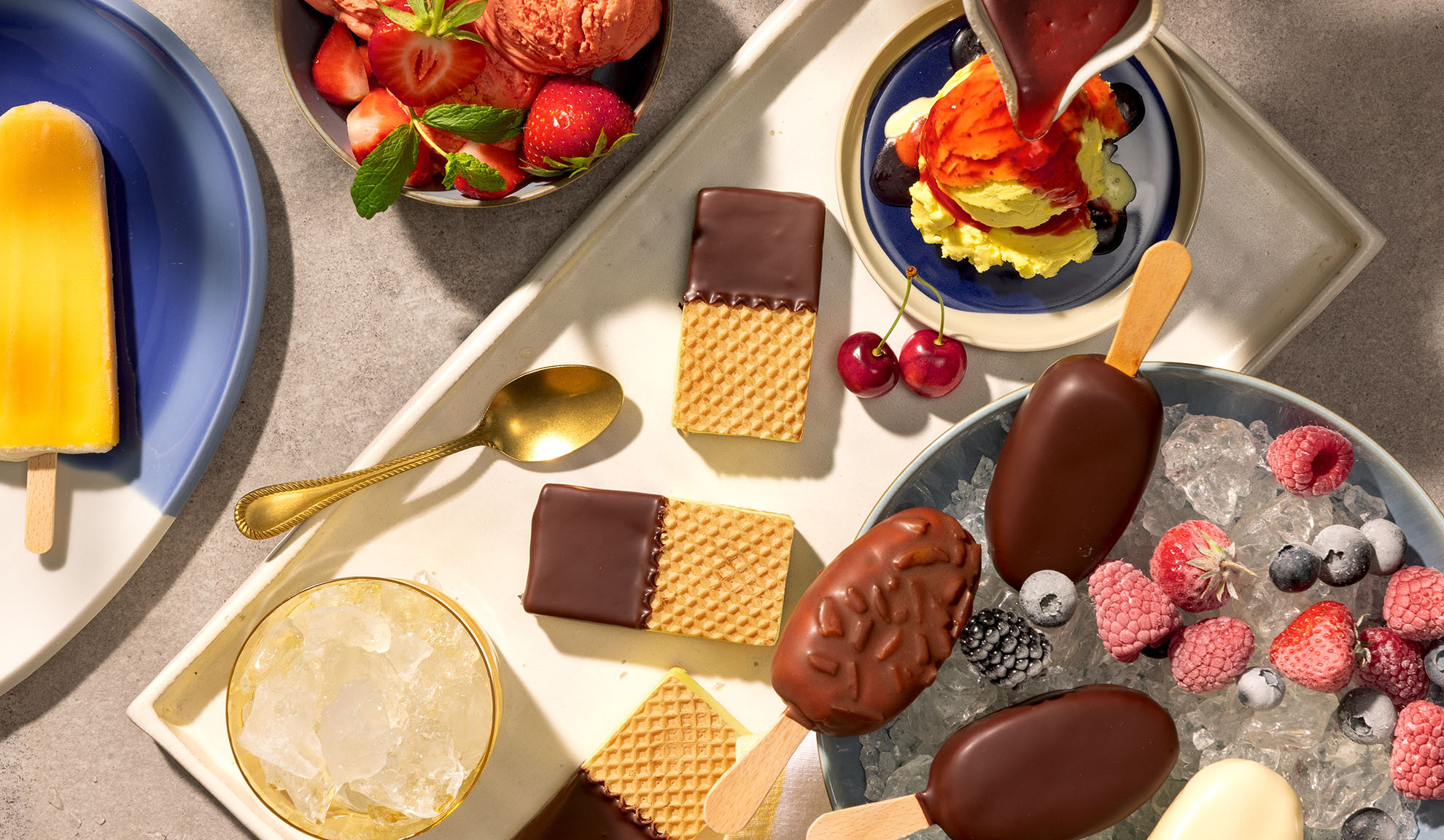 Assortimento di gelati, ghiaccioli, wafer e frutti di bosco su un vassoio.