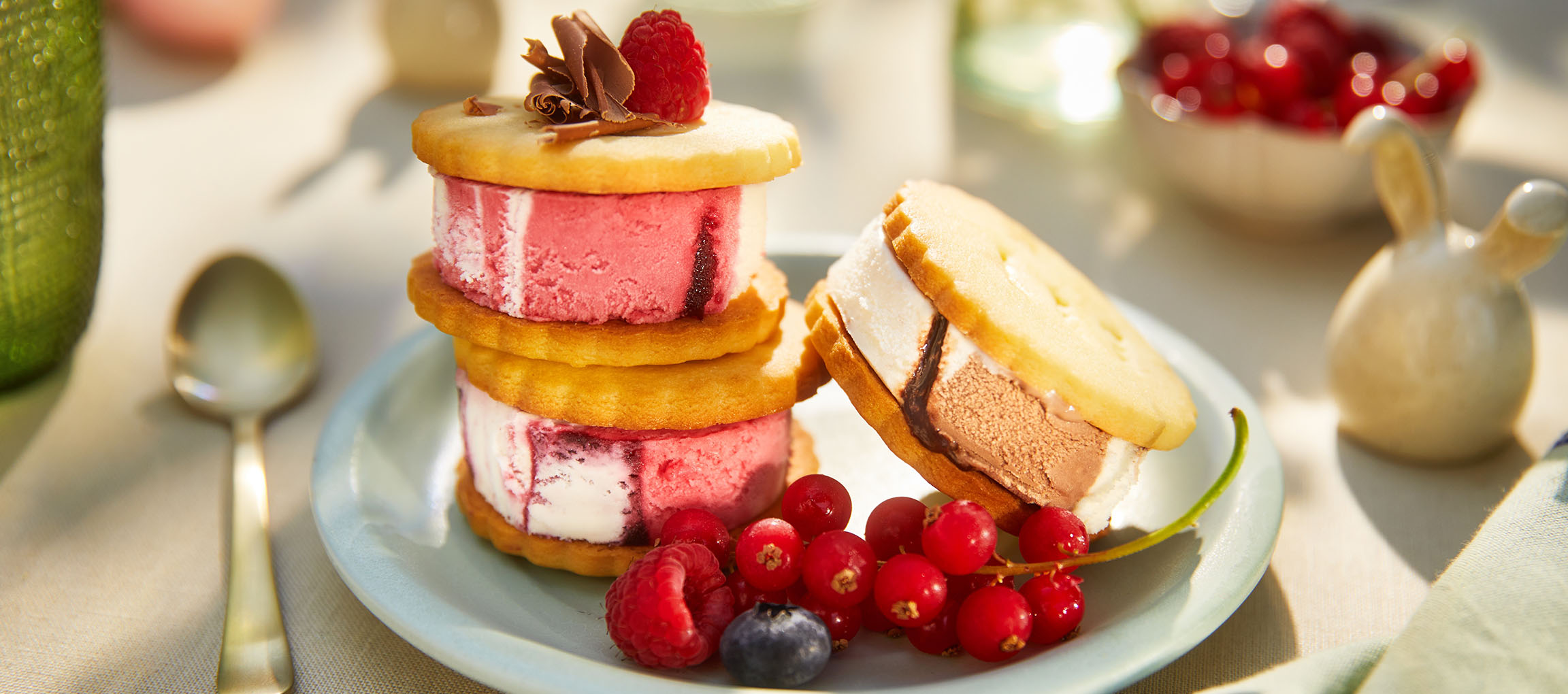 Sandwich di gelato con frutti di bosco su un piatto azzurro in un ambiente esterno soleggiato.