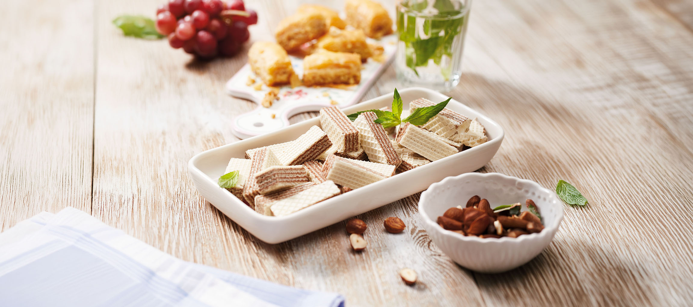 Wafer, baklava, uva e acqua alla menta su un tavolo di legno.